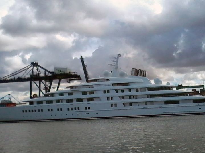 The long white superyacht Azzam moored in a harbour under a cloudy sky