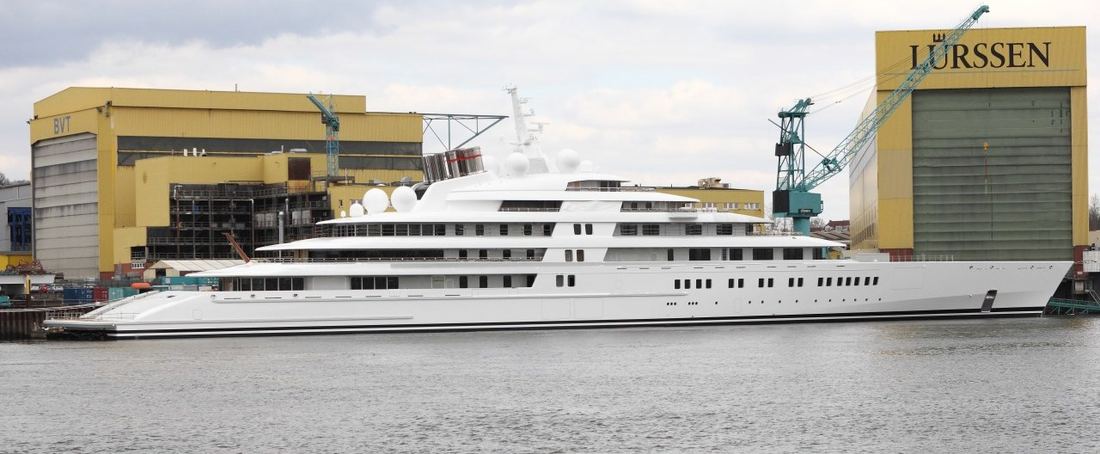 Azzam moored beside the large yellow Lürssen shipyard halls in Bremen