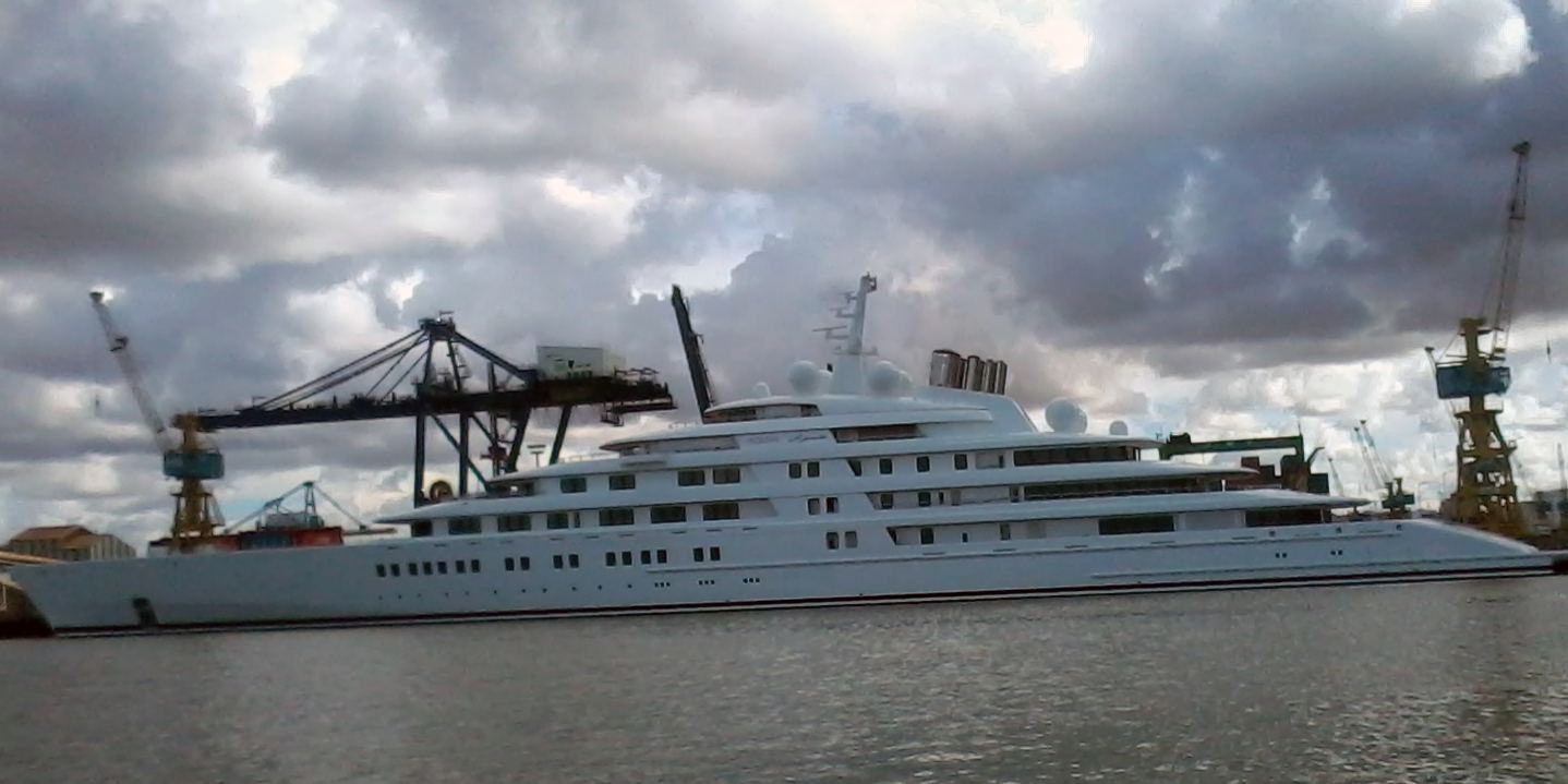 The long white superyacht Azzam moored in a harbour under a cloudy sky