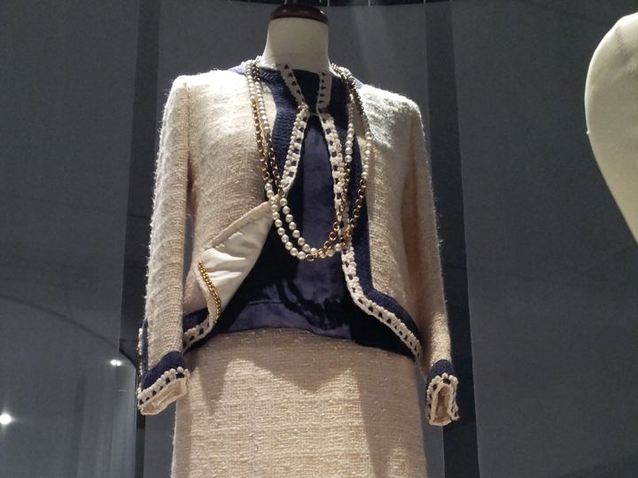 A cream wool tweed Chanel suit with a black silk blouse displayed on a mannequin