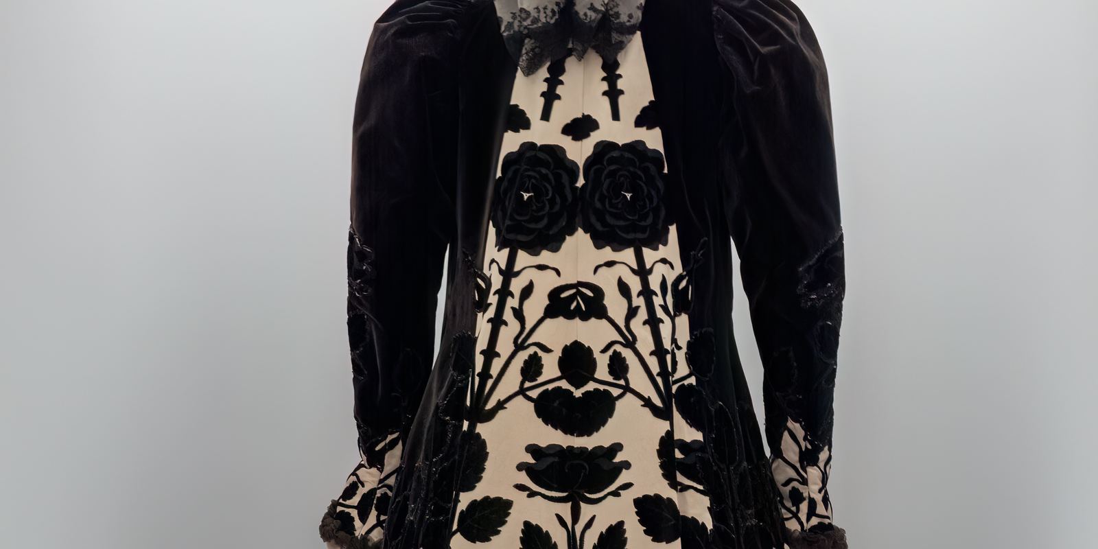 A House of Worth evening coat from about 1900 in cream satin with a bold black velvet rose pattern