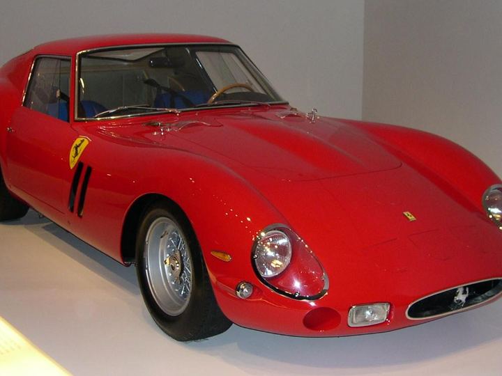 A red 1962 Ferrari 250 GTO coupe on display, seen from the front three-quarter angle