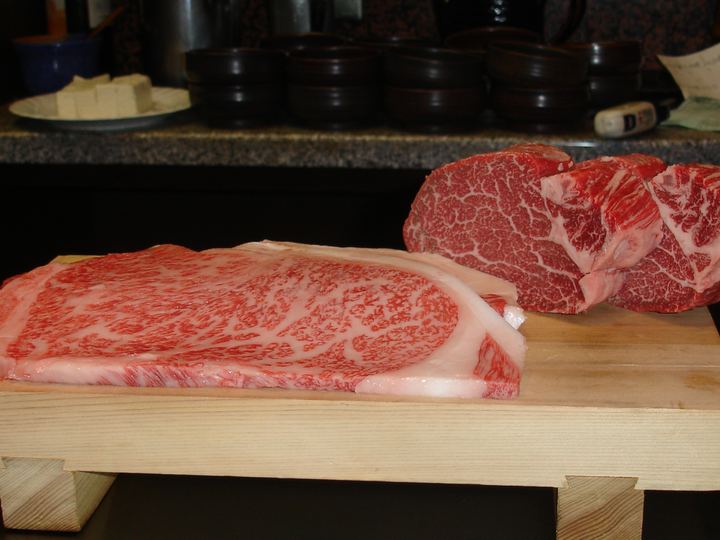 Thick slices of richly marbled Kobe beef on a wooden board