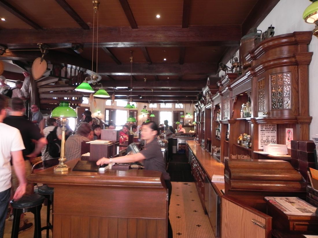 Guests at the long wooden counter of the Long Bar at Raffles Hotel