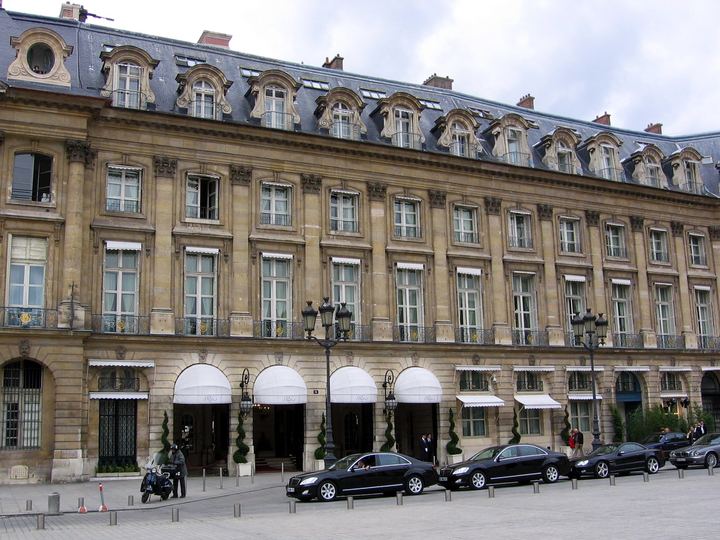 The stone facade of the Hôtel Ritz Paris with white awnings over its arched entrances