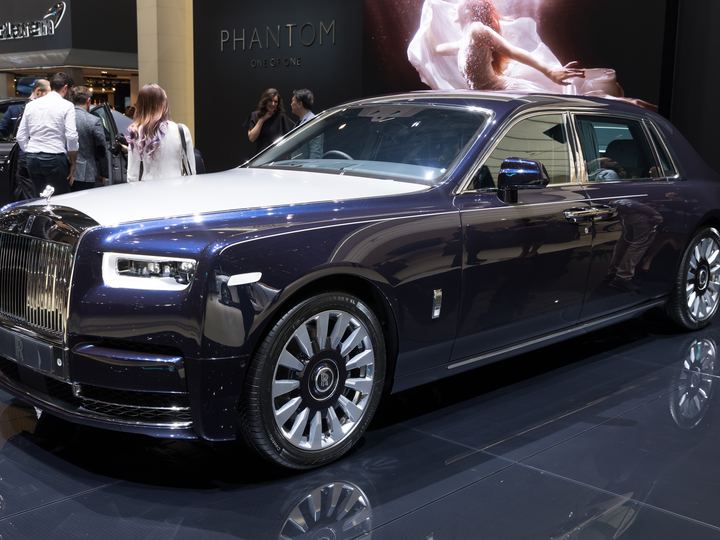 A dark blue Rolls-Royce Phantom VIII on a motor show stand
