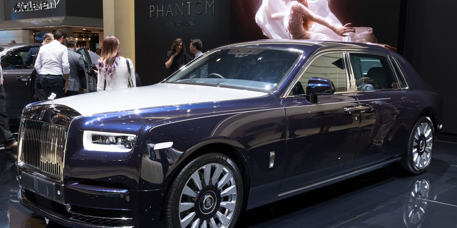 A dark blue Rolls-Royce Phantom VIII on a motor show stand